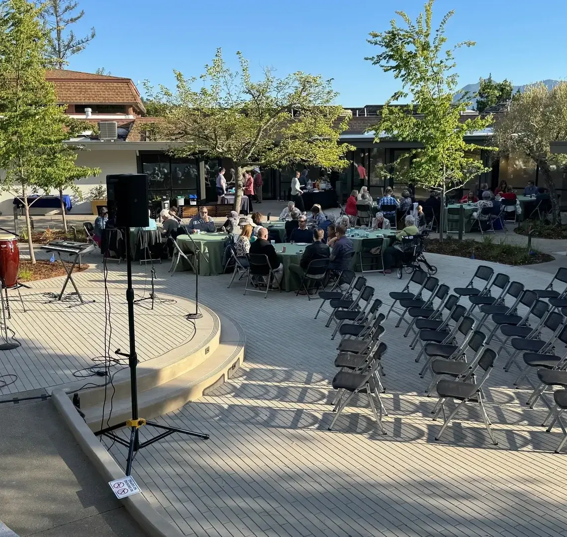 Outdoor event with chairs and people gathered.