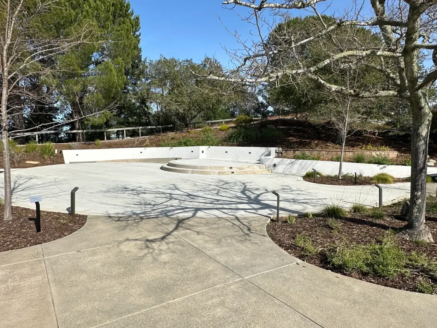 Empty outdoor amphitheater surrounded by trees.