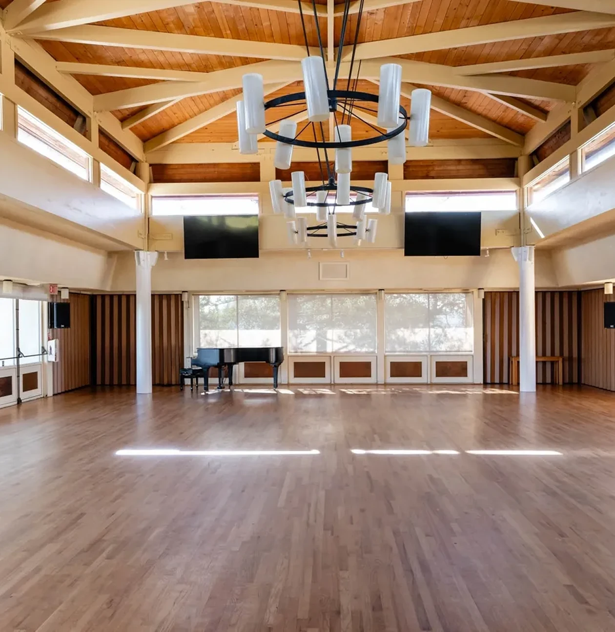 Spacious room with piano and wooden ceiling.