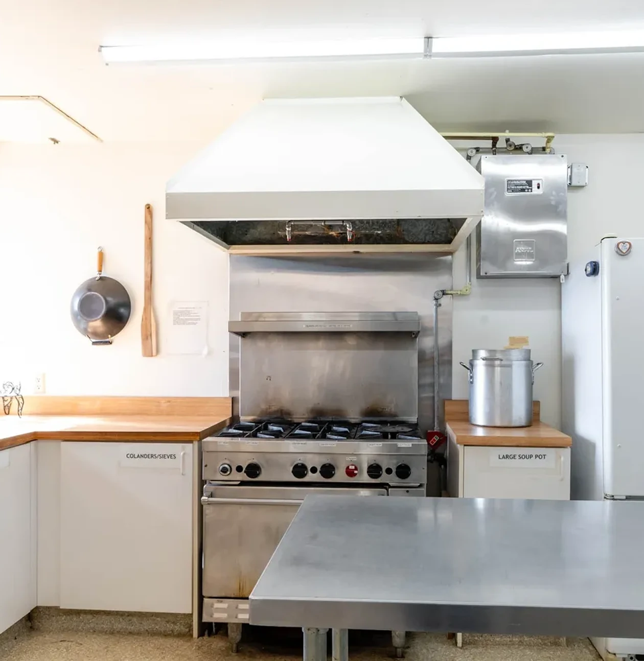 Commercial kitchen with stove and stainless steel table.