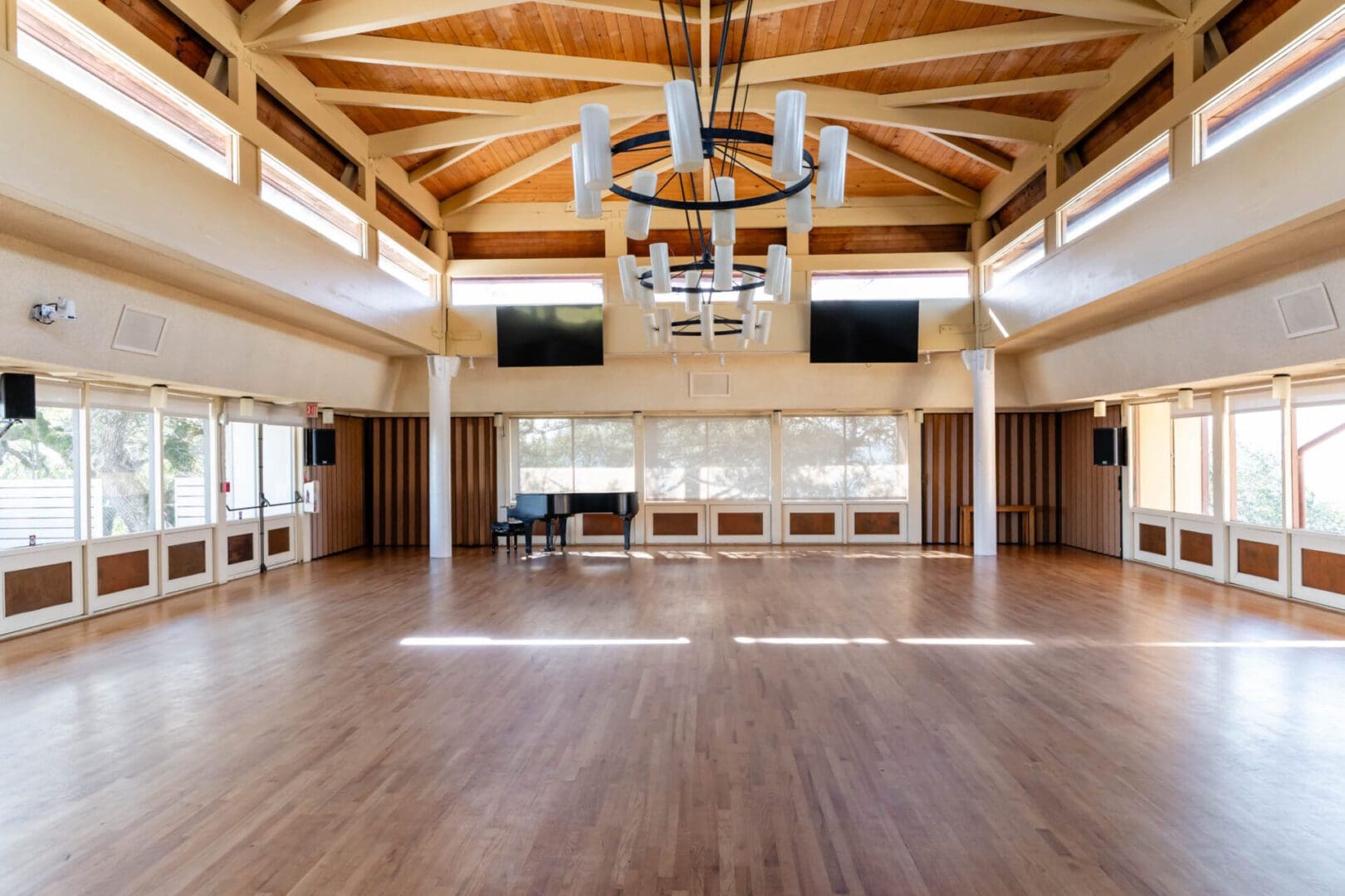 Spacious hall with wooden floor and piano.