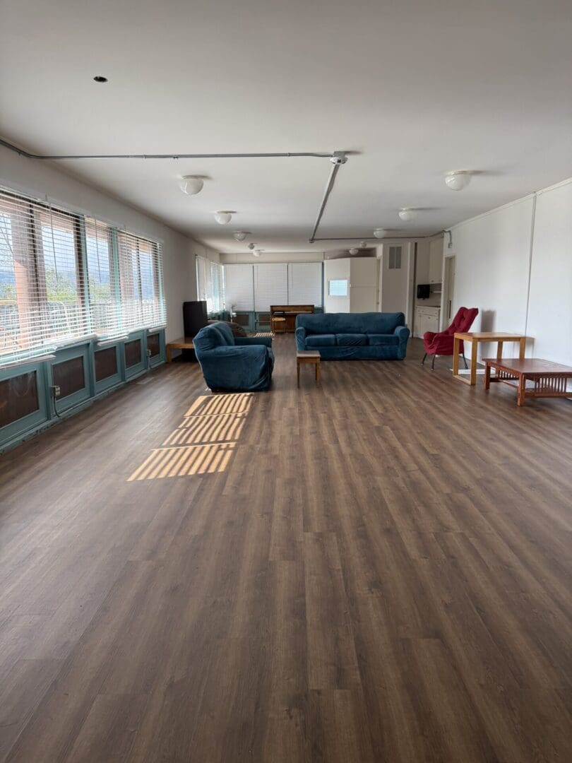 Spacious room with sofas and wooden floor.